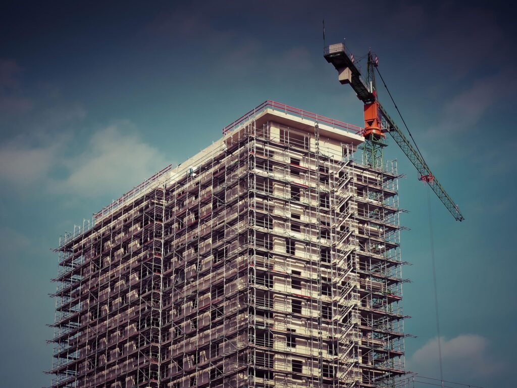 Vaakesan Gunaratnam inspecting a high-rise modular construction site with scaffolding and tower crane under clear sky